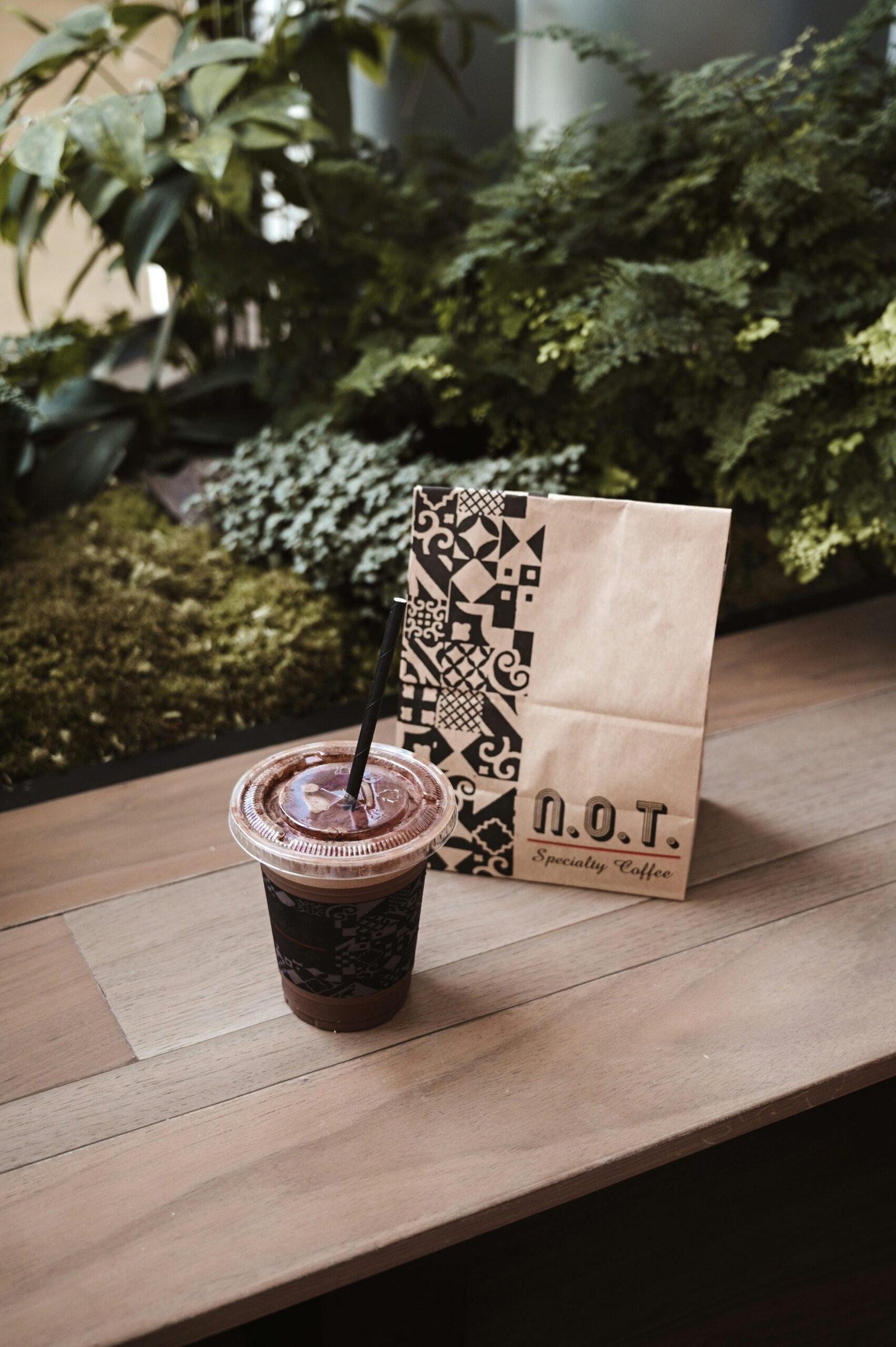 brown paper bag with black straw on brown wooden table